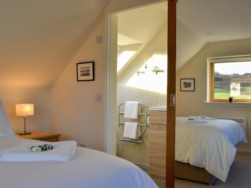 a bedroom with two beds and a mirror at Rowan House in Fiskavaig
