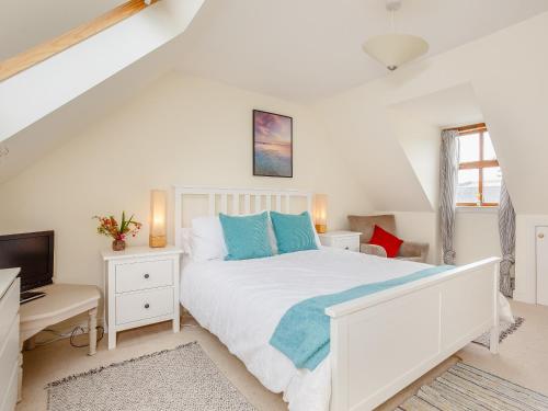 a white bedroom with a white bed and a television at Caldon Cottage in Cromarty