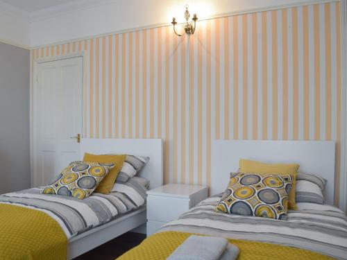 - 2 lits dans une chambre à rayures orange et blanche dans l'établissement Turnstone House, à Gorleston-on-Sea