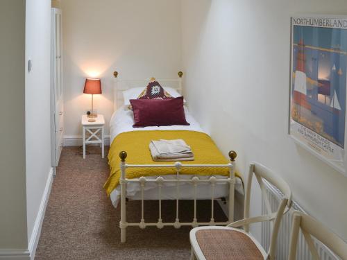 a small bedroom with a bed with a yellow blanket at Croft Cottage in Sharperton