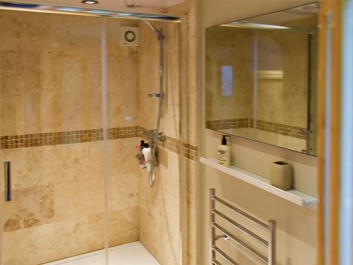 La salle de bains est pourvue d'une douche avec une porte en verre. dans l'établissement Owls Rest, à Burley in Wharfedale