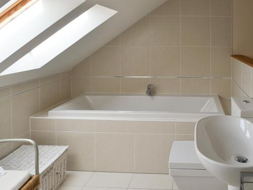 a bathroom with a bath tub and a sink at Stable Cottage in Chatton