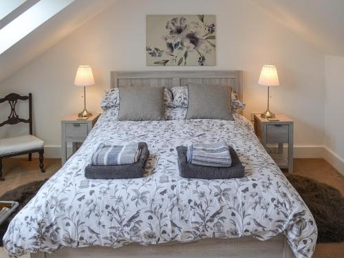 a bedroom with a large bed with two lamps at Stable Cottage in Chatton