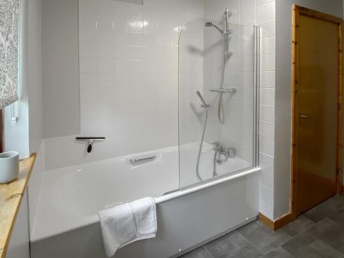 a white bathroom with a shower and a tub at Kintulloch in Insh