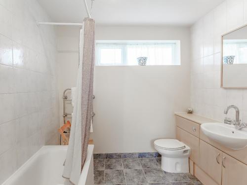 ein weißes Bad mit einem WC und einem Waschbecken in der Unterkunft Blossoms Cottage in Albourne