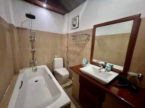 a bathroom with a tub and a sink and a mirror at Lakhang Thong Hotel in Luang Prabang