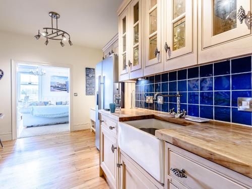 a kitchen with a sink and blue tiles on the wall at Apartment 1 - Uk32244 in Aberdyfi