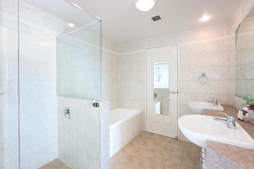 een badkamer met een bad, een wastafel en een douche bij Sun City Spacious Sleeps 4 in Gold Coast