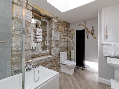 a bathroom with a stone wall with a toilet and a sink at Creebank in Newton Stewart