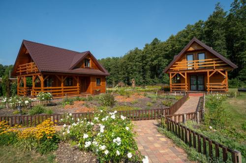 una cabaña de madera con un jardín frente a ella en Uroczysko Trzyrzeczki, en Dąbrowa Grodzieńska-Wieś