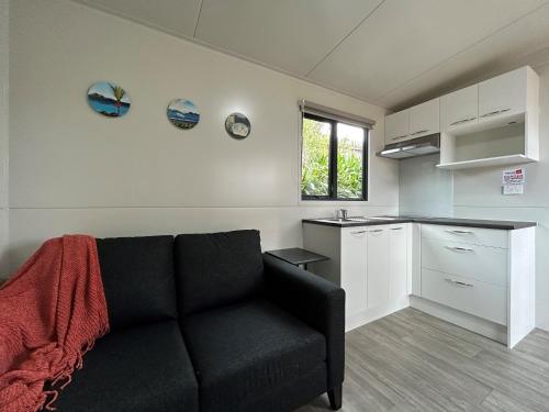 a living room with a couch and a kitchen at Takapuna Beach Holiday Park in Auckland
