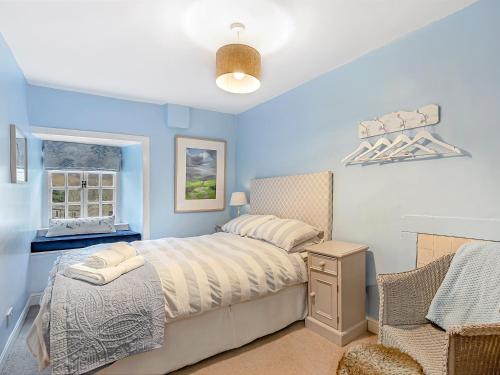 a blue bedroom with a bed and a chair at Wellside Cottage in Starbotton