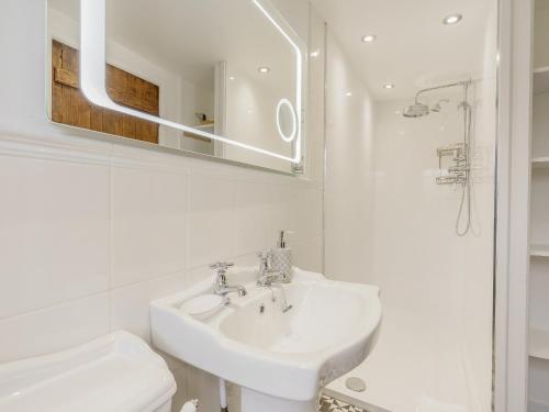 W białej łazience znajduje się umywalka i lustro. w obiekcie Duck Island Cottage w mieście Ringwood