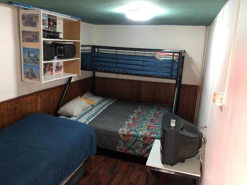ein kleines Schlafzimmer mit einem Bett und einem TV. in der Unterkunft Hernanparapente like your home in Iquique