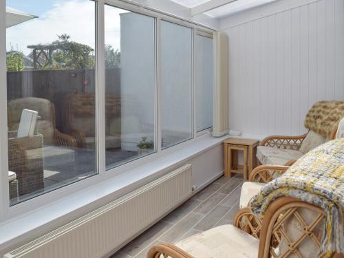 Habitación con ventana grande con sillas y mesa. en Sea Dreams, en Saundersfoot