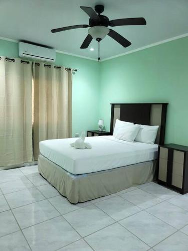 Schlafzimmer mit einem großen Bett und einem Deckenventilator in der Unterkunft Spacious & Spotless new house, 4 BRs in Roatán