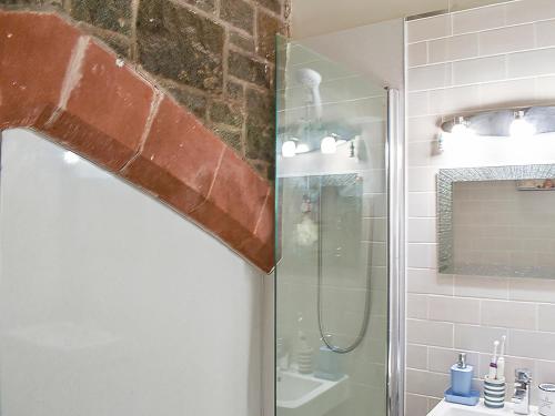 y baño con ducha y puerta de cristal. en White Sands, en Criccieth