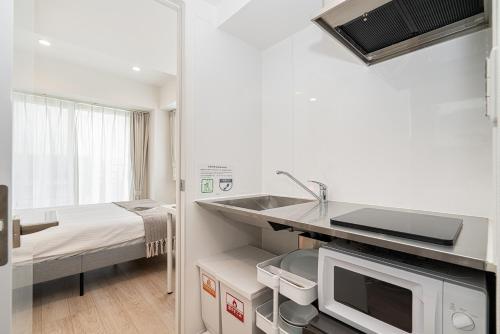a small kitchen with a sink and a microwave at ZAITO Tokyo Skytree Yokokawa III 錦糸町駅から徒歩９分 in Tokyo