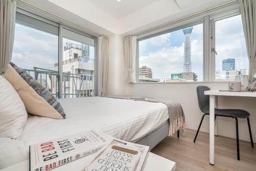 a bedroom with a bed and a desk and windows at ZAITO Tokyo Skytree Yokokawa III 錦糸町駅から徒歩９分 in Tokyo
