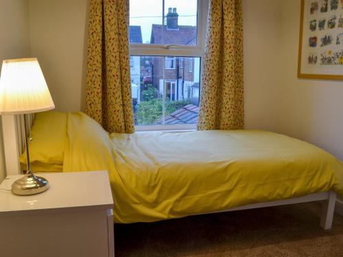 a bedroom with a yellow bed and a window at Scira in Sheringham