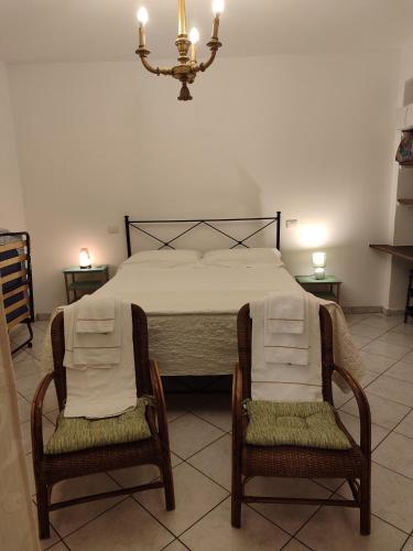 a bedroom with a bed with two chairs and a chandelier at Happy Flat in Riparbella