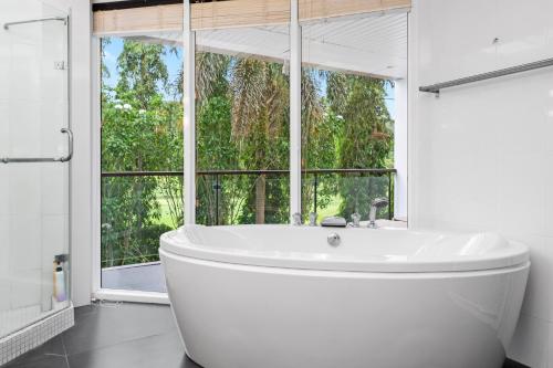 a white bath tub in a bathroom with a window at The Fairways Villas - 4 bedroom for 10 guests - 7kms to Patong beach in Kathu
