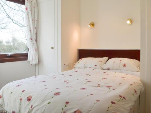 a bedroom with a bed with a floral comforter and a window at Chalet 1 - Uk30302 in Tore