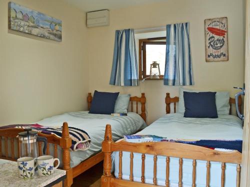 um quarto com 2 camas individuais e uma janela em Stonechat Barn em Pancrasweek