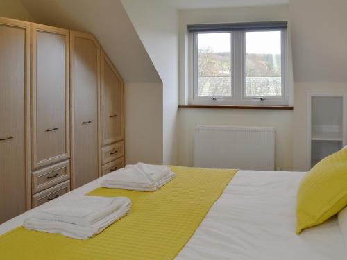 a bedroom with a bed with yellow sheets and a window at Crofters Cottage in Rothbury