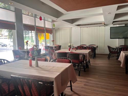 Neo Hatyai Hotel في هات ياي: مطعم بطاولات وكراسي وتلفزيون بشاشة مسطحة