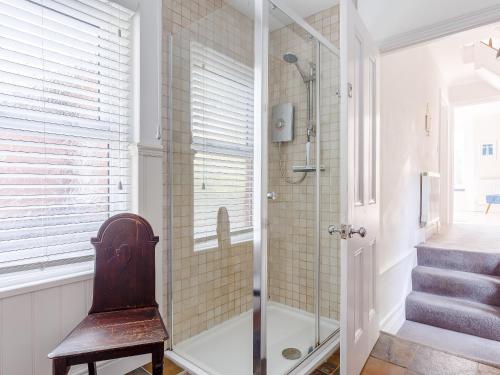 a bathroom with a shower and a wooden chair at Tell Tails in Dartmouth