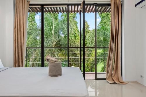The Fairways Villas - 4 bedroom for 10 guests - 7kms to Patong beach في كاتو: غرفة نوم بسرير ونافذة كبيرة