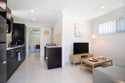 a living room with a couch and a tv and a kitchen at Modern & Beautifully Presented! Close to Transport in Brisbane