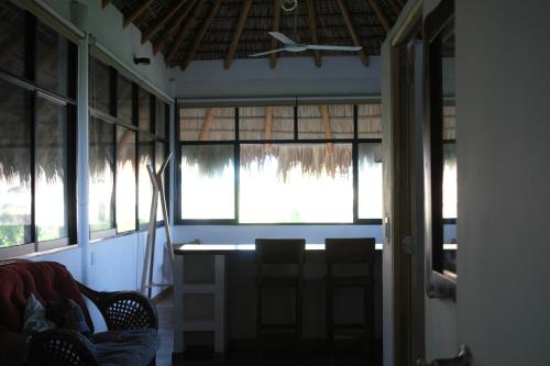 a room with a table and some chairs and windows at Casa shanti penthouse with AC in Puerto Escondido