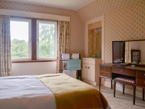 - une chambre avec un lit, un bureau et un miroir dans l'établissement Braehead, à Nairn