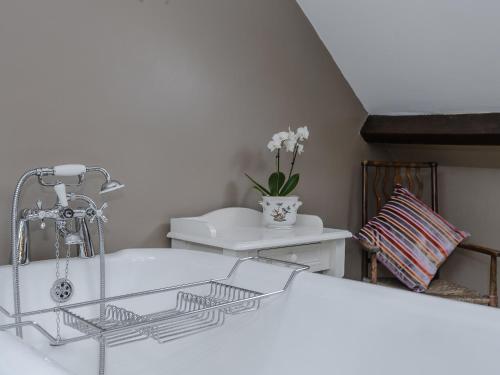 a white bathroom with a tub and a sink at The Old Saddlery in Colkirk