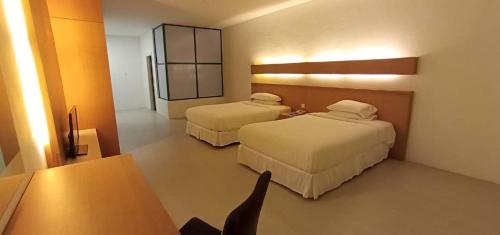 una camera d'albergo con due letti e un tavolo di Ara Hotel a Bau