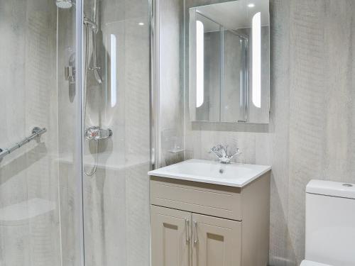 a white bathroom with a sink and a shower at The Old Toll House in Portpatrick