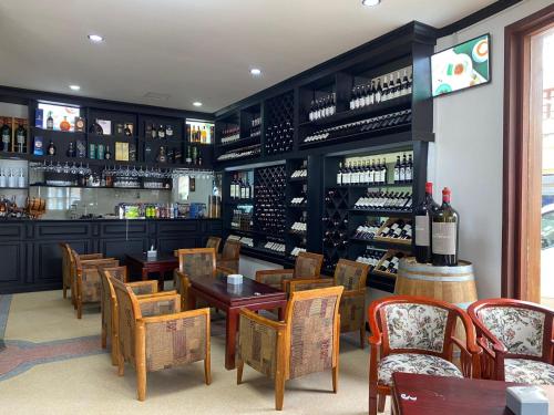 a bar with wooden tables and chairs and wine bottles at SUBINH HOTEL AND RESTAURANT in Pakse