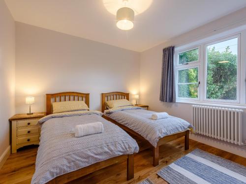 two beds in a bedroom with a window at Beach Holme in East Wittering