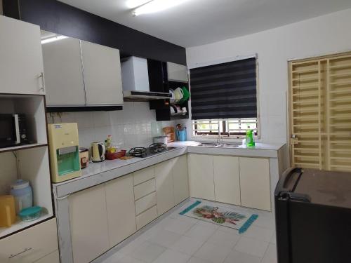 een kleine keuken met witte kasten en een raam bij Nilai Impian Homestay @ Dillenia in Nilai