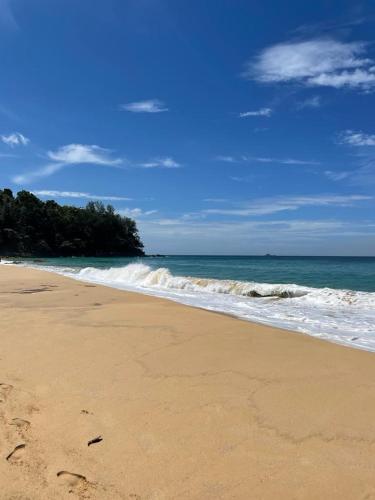 a sandy beach with waves in the ocean at WERT in Phuket Town