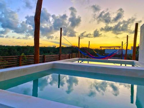 a swimming pool with a hammock and the sunset at RELAX TULUM Family Friendly Apartment in the in the jungle - pools & cenotes in Tulum