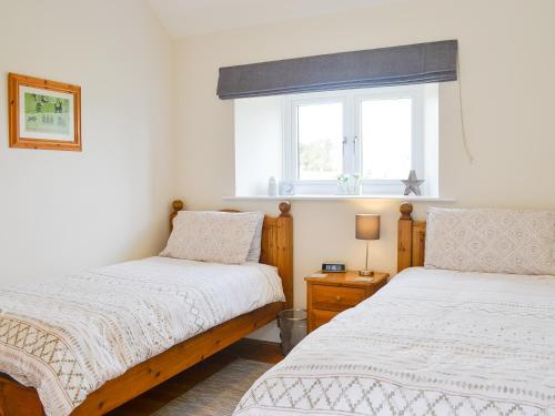 1 dormitorio con 2 camas y ventana en Stanegate Cottage en Greenhead