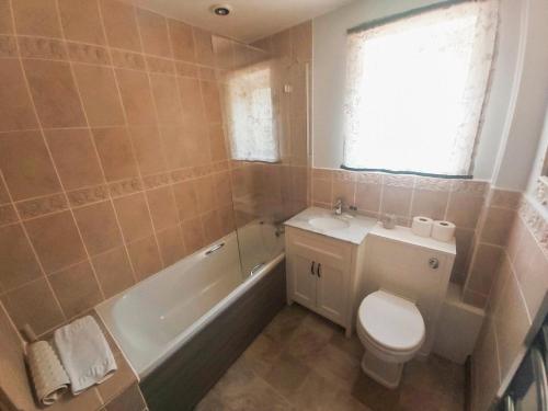 a bathroom with a toilet and a tub and a sink at Carrot Cottage - Uk32609 in Manton