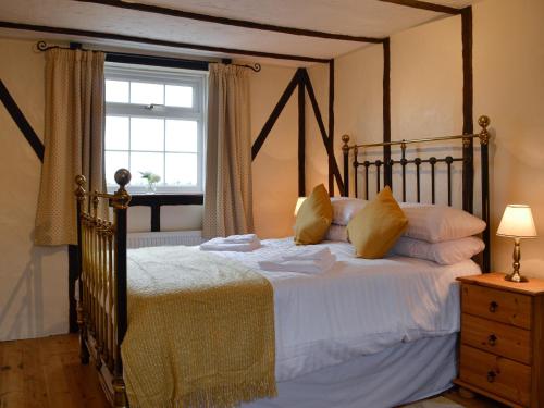 a bedroom with a bed with white sheets and a window at Tollgate Cottage in Blythburgh