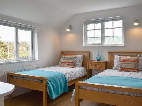 two beds in a room with two windows at Purbeck Apartment in Chideock