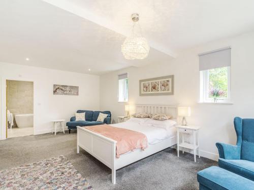 a bedroom with a bed and two blue chairs at High Trees View in Knaresborough