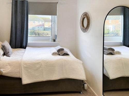 a bedroom with two beds and a mirror at Waters Edge Holiday Home in Beadnell