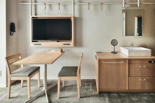 a bathroom with a table and a sink and a tv at REF Matsuyama City Station by VESSEL HOTELS in Matsuyama